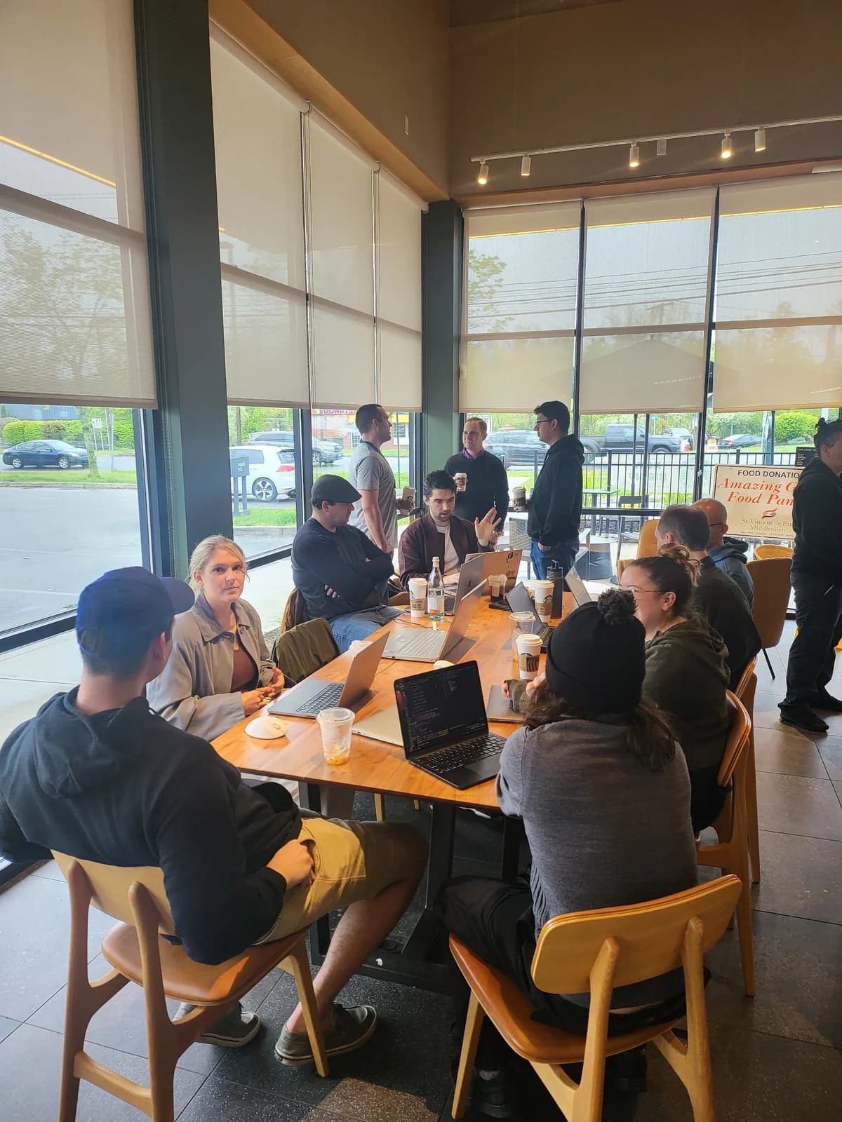 Software community members sharing ideas around a café table with open laptops.