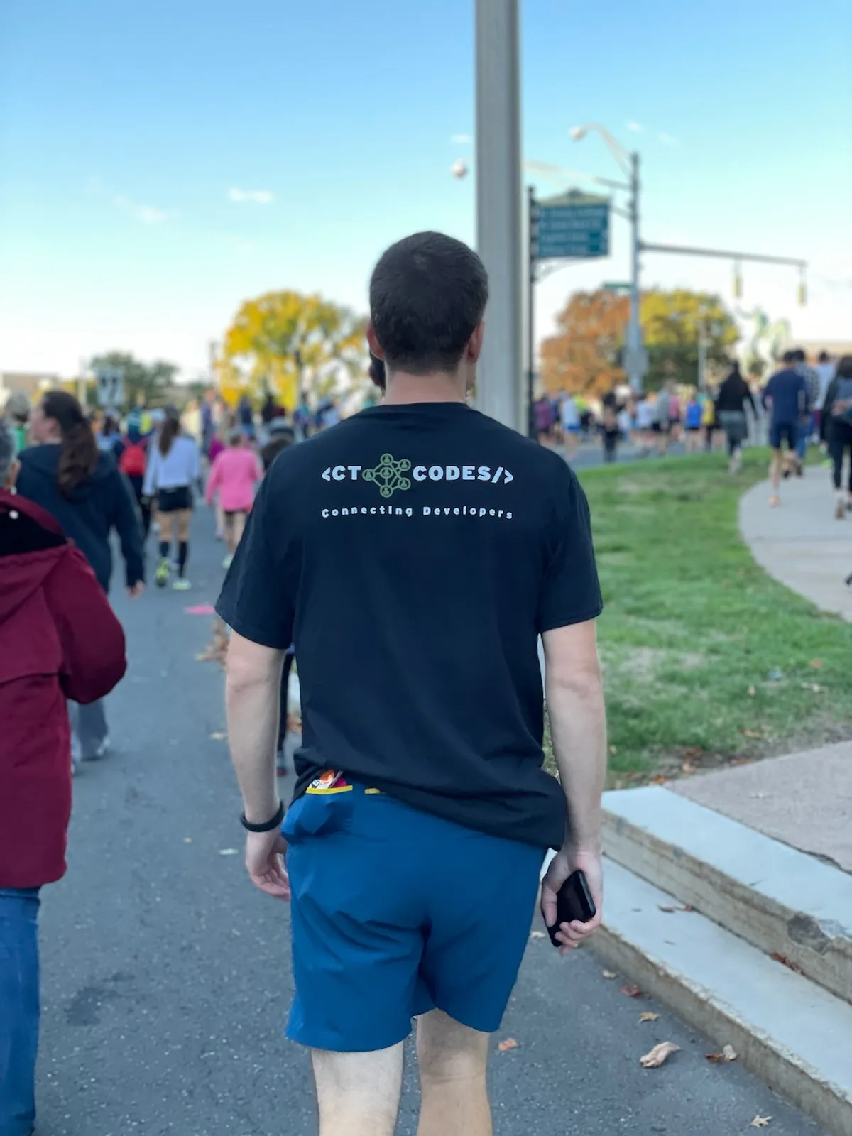 A person wearing a CT Codes Connecting Developers shirt at an outdoor gathering.